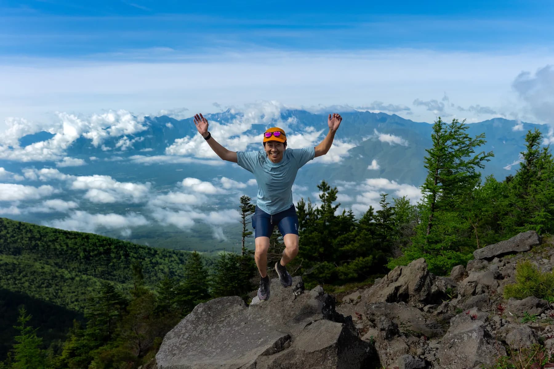 A runner with arms raised above a sea of cloud