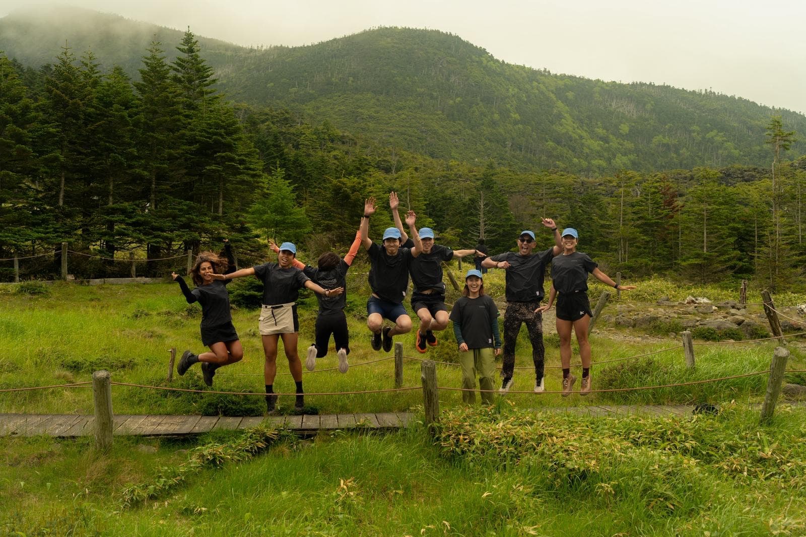 Goodpace runners jumping off a boardwalk with mountains behind them